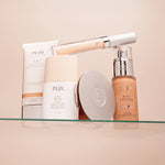 Assorted PUR 4-in-1 beauty products including tinted moisturizer SPF 20, skin tint, foundation and compact on a glass shelf.