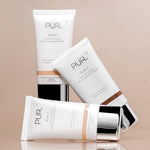 4-in-1 PUR Tinted Moisturizer tubes with SPF 20 on white packaging and silver caps arranged in a stylish display against beige-tan background
