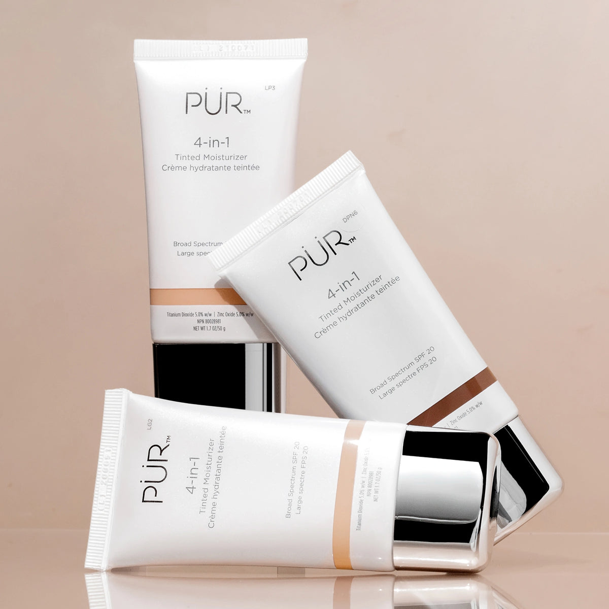 4-in-1 PUR Tinted Moisturizer tubes with SPF 20 on white packaging and silver caps arranged in a stylish display against beige-tan background