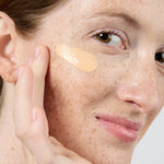 Close-up of a woman applying a beige concealer stick to her face Shade LG3  