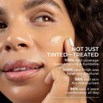 Close-up of a model's face applying PÜR 4-in-1 Skin Tint swatch to her cheek with a fingertip for a radiant, hydrated finish. Independent study found that 100% said coverage looked natural and buildable. 100% said finish as balanced. 96% said it wore comfortable all day.
