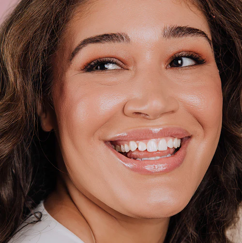 close up shot of model wearing glossy lip tint and smiling