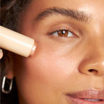 Close-up of a pink Silky Tint Creamy Multitasking Blush Stick with Peptides in You Go Pearl shade being applied to the cheek.