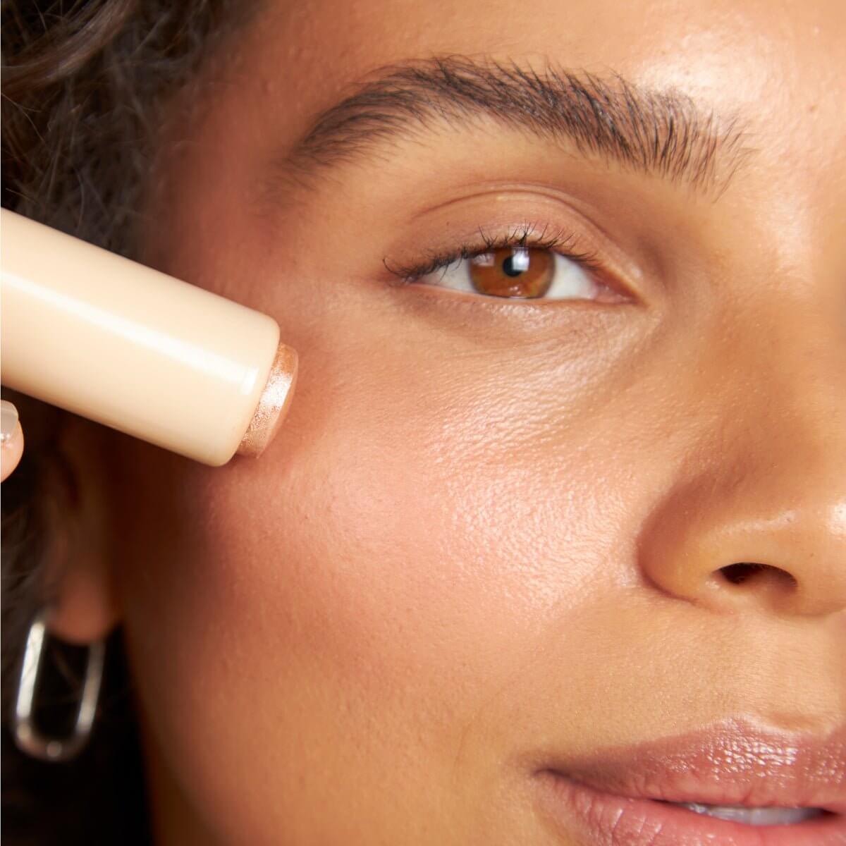 Close-up of a pink Silky Tint Creamy Multitasking Blush Stick with Peptides in You Go Pearl shade being applied to the cheek.